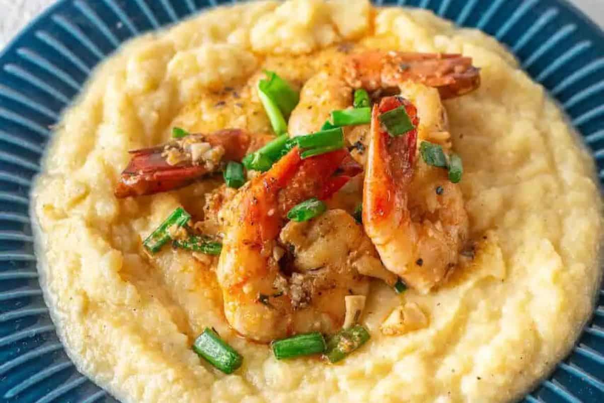 Enjoy a restaurant-quality experience with shrimp and chopped green onions nestled on a bed of creamy grits, elegantly served on a blue plate.