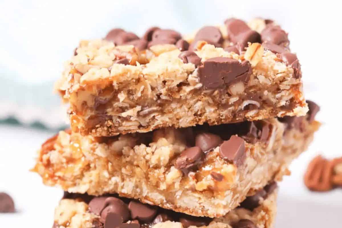 Three stacked chocolate chip and oatmeal bars, resembling blondies, with visible nuts against a light background.