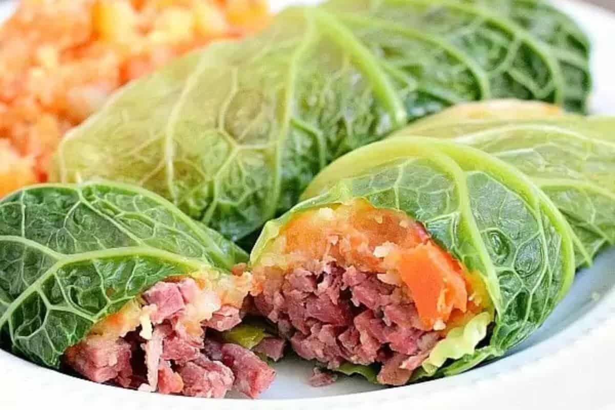 Stuffed cabbage leaves filled with minced meat and vegetables, partially sliced to reveal the filling, evoke a nod to traditional recipes. This modern take on classic flavors is served elegantly on a white plate.