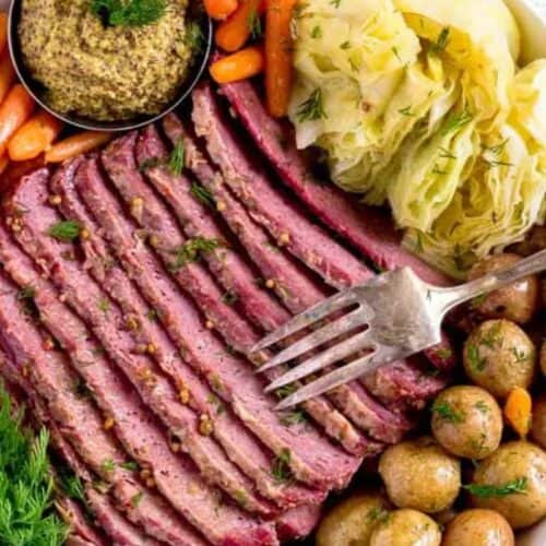 A plate of sliced corned beef and cabbage, accompanied by boiled potatoes, carrots, and a small dish of mustard, garnished with fresh dill. This dish beautifully blends traditional recipes with a touch of modern flair.