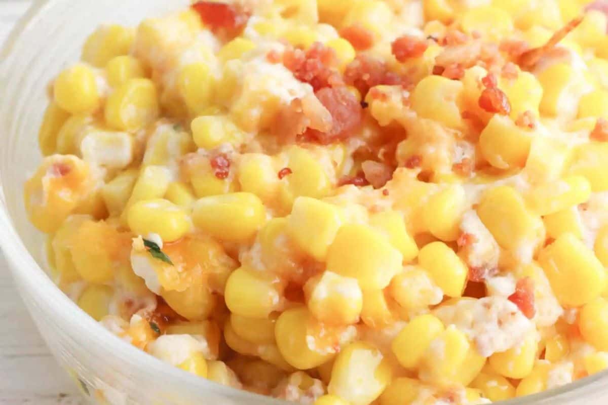 A bowl of creamy corn casserole with bacon pieces and cheese, perfect for St. Patrick's Day or any potluck gathering.
