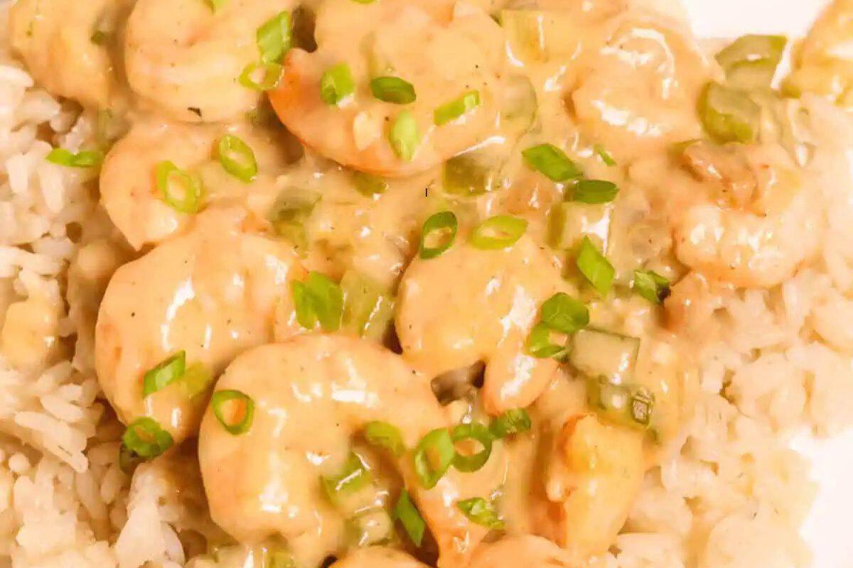 Plate of creamy shrimp served over rice, garnished with chopped green onions.