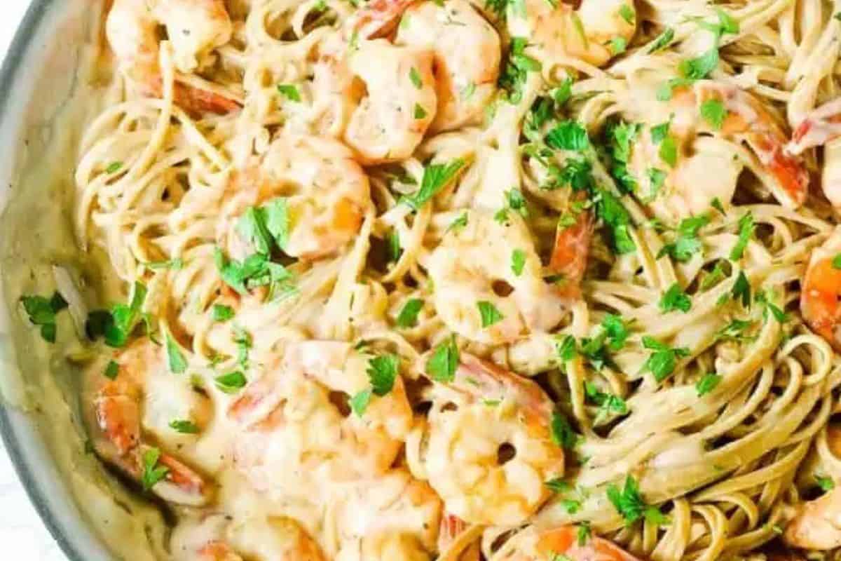 Enjoy restaurant-quality shrimp alfredo in a creamy sauce, garnished with chopped parsley and served in a skillet.