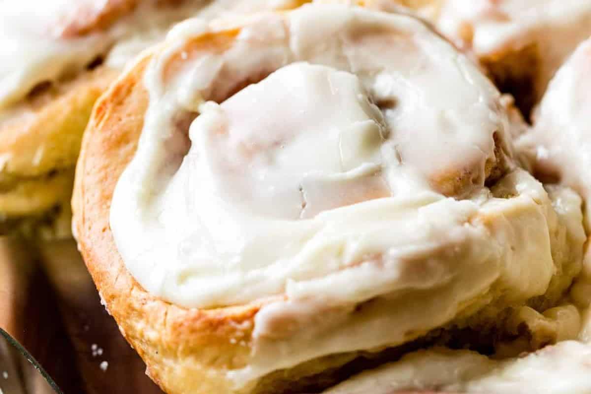 Close-up of a giant cinnamon roll, topped with a sweet white icing.