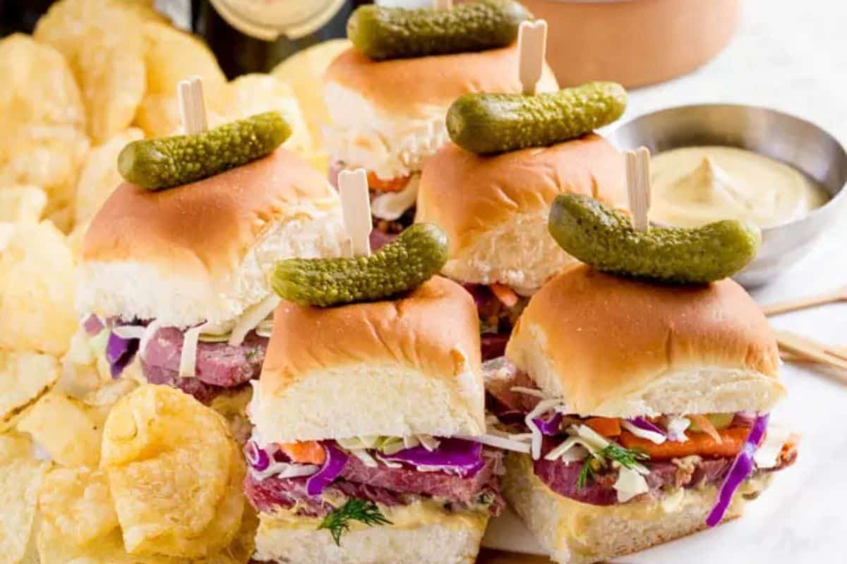 Enjoy these sliders featuring corned beef, coleslaw, and pickles atop a warm bun, all served with a side of crispy potato chips and mustard dip. A delightful twist on traditional recipes that marries classic flavors with modern flair.