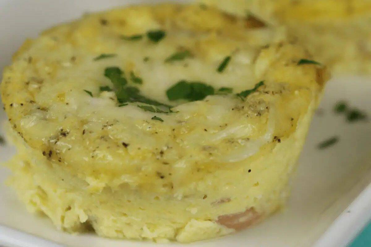 A close-up of a delectable egg cup topped with vibrant herbs on a white plate, perfect for a brunch delight.