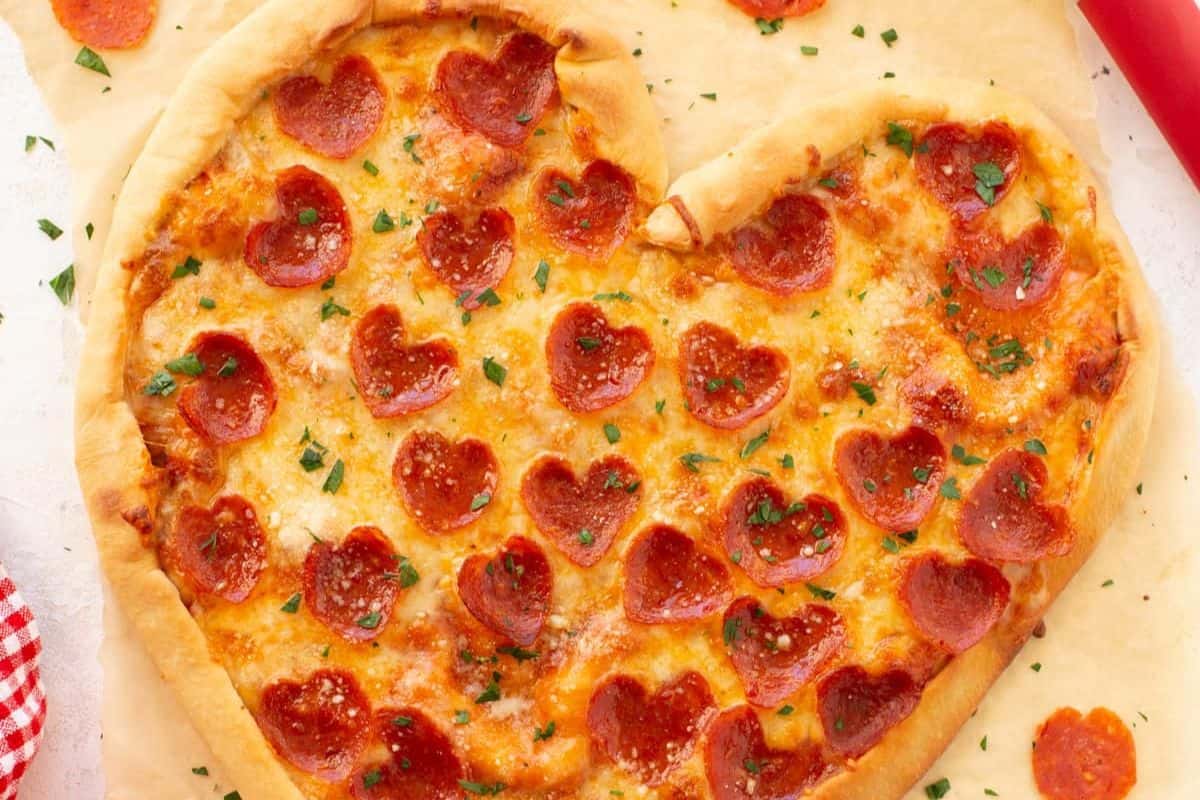 Celebrate Galentine’s Day with a heart-shaped pizza, topped with heart-shaped pepperoni slices and sprinkled with herbs—a festive recipe perfect for sharing with your bestie.