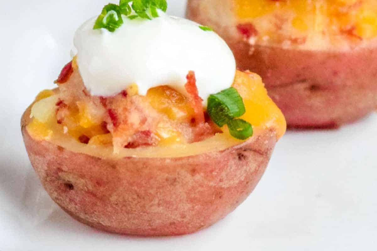 A crowd-pleasing Irish potato bite topped with melted cheese, sour cream, bacon bits, and chopped green onions—a perfect addition to your potluck recipes.