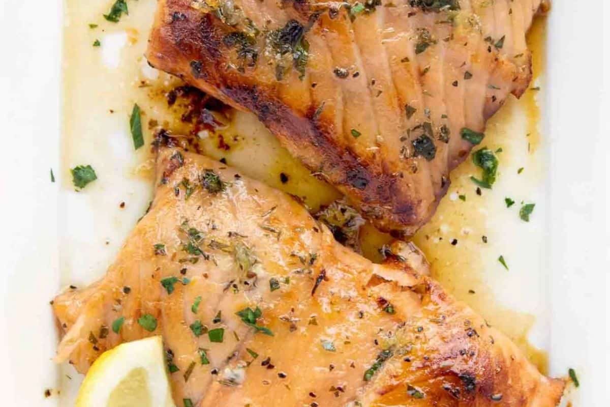 Two cooked salmon fillets garnished with herbs and a lemon wedge rest on a white plate, offering an Irish-inspired twist to classic comfort food.