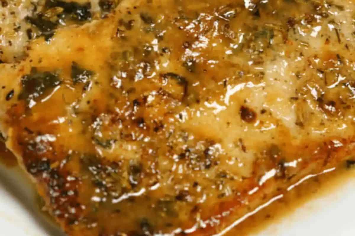 Pan-seared pork chop with a rich sauce, herbs, and visible seasonings.