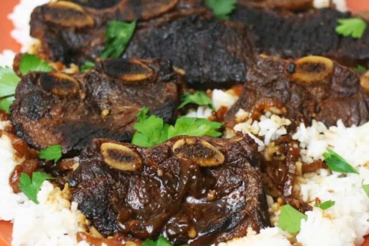 Grilled beef short ribs with visible bones served on white rice, garnished with fresh parsley leaves—an easy dinner inspired by classic slow cooker recipes.