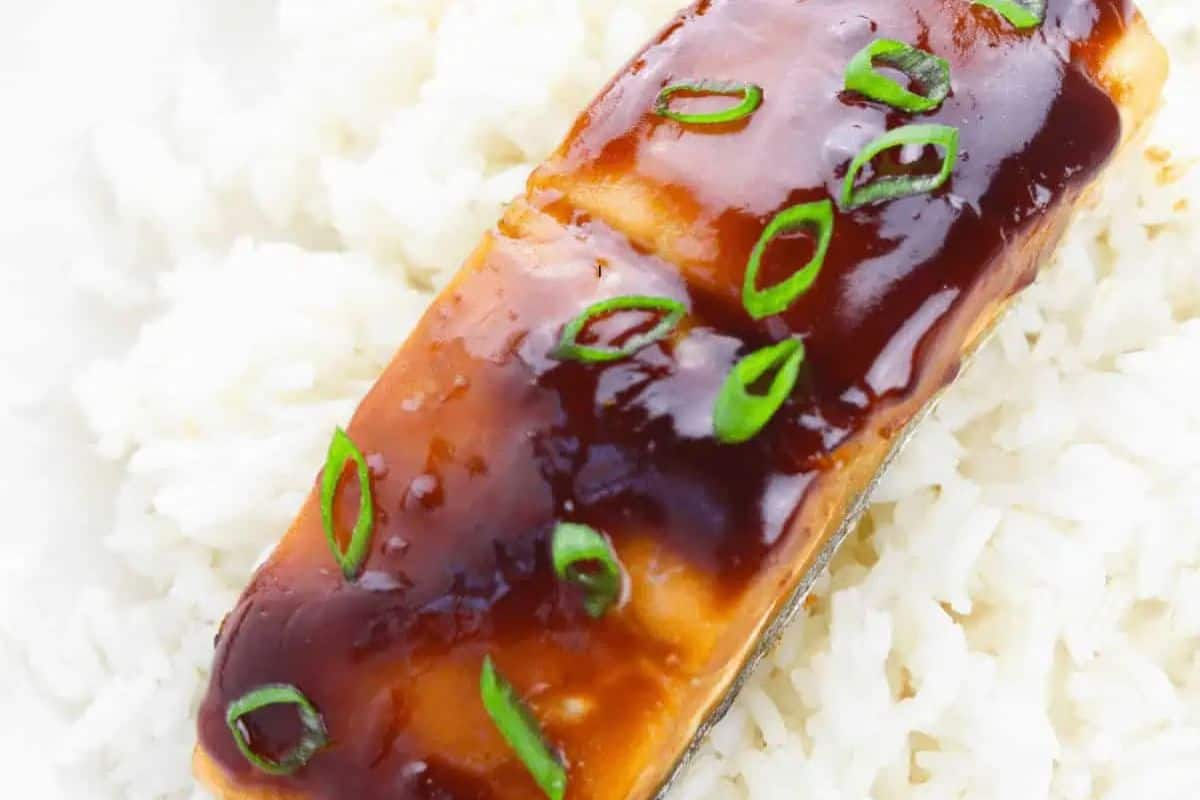 Salmon with a rich maple glaze, garnished with chopped green onions, served on a bed of fluffy white rice.