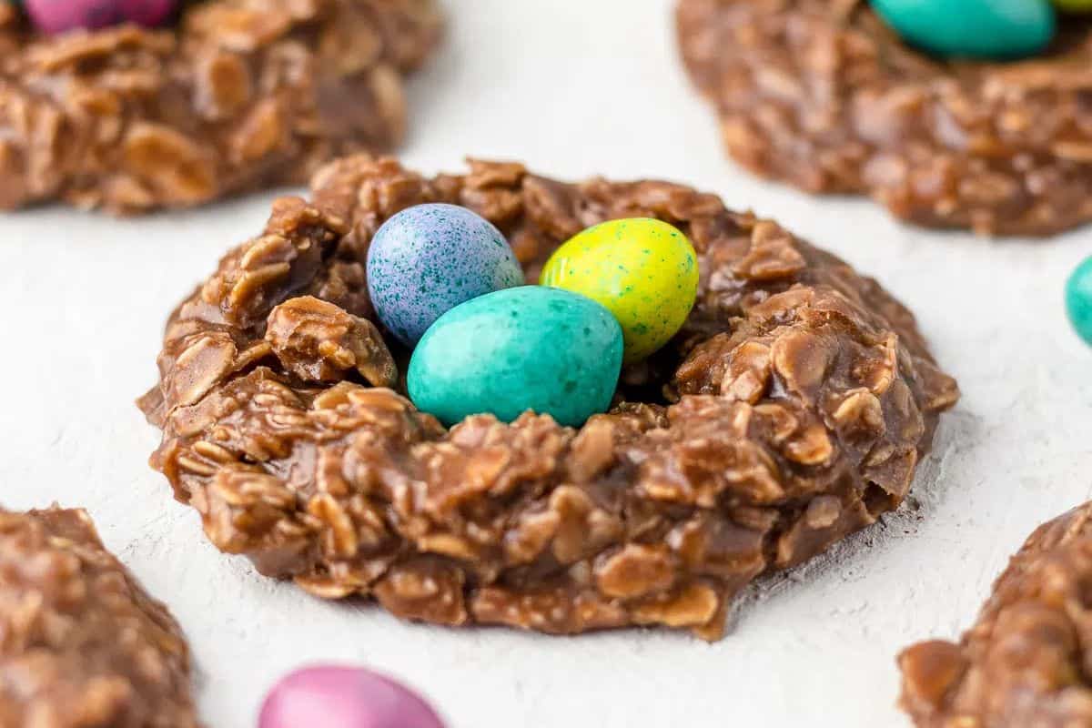 No-bake chocolate oatmeal cookie shaped like a nest, topped with three colorful, speckled candy eggs. This delightful creation takes your dessert game to the next level with its charming presentation and effortless preparation.