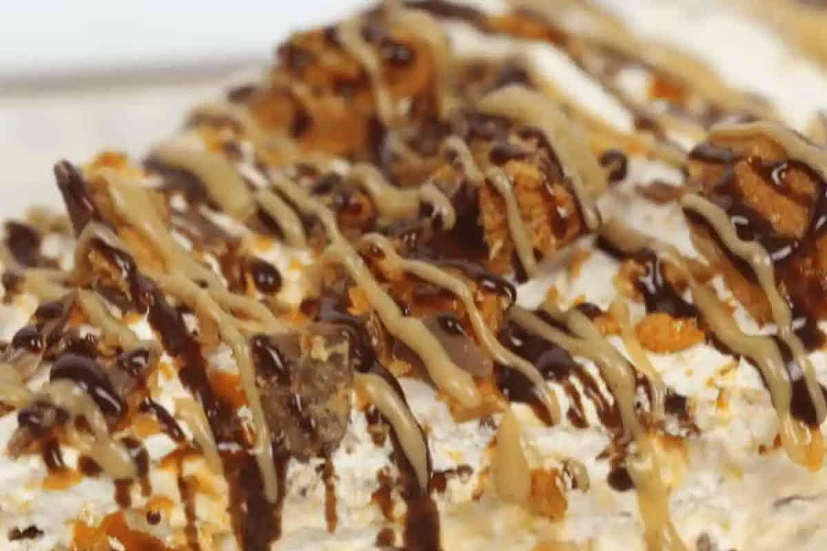 A close-up of an easy no bake butterfinger pie features a tempting mix of drizzled chocolate and caramel sauces, sprinkled with crumbled cookies or nuts. Perfect for those looking to up their dessert game without turning on the oven, this no-bake treat is pure indulgence in every bite.