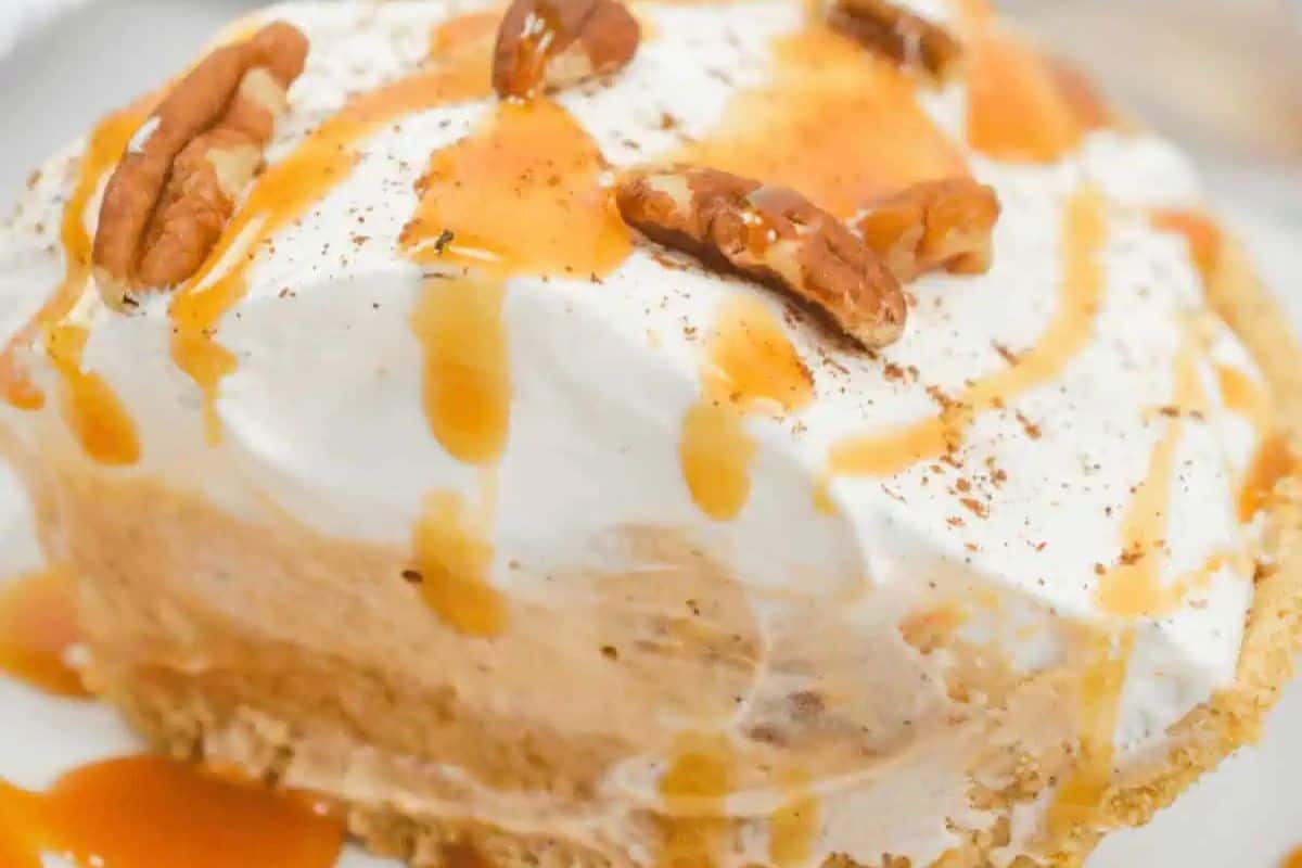 This delightful no-bake butterscotch cinnamon pie features a crumbly crust topped with whipped cream, drizzled with caramel sauce, and garnished with pecans. Elevate your dessert game effortlessly!.