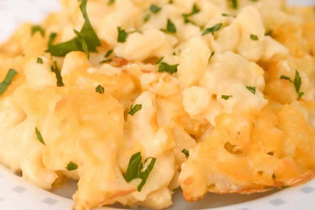 Close-up of a plate of crowd-pleasing macaroni and cheese garnished with chopped parsley. The dish appears creamy with visible melted cheese and small pasta pieces, making it an ideal choice for potluck recipes that delight everyone.