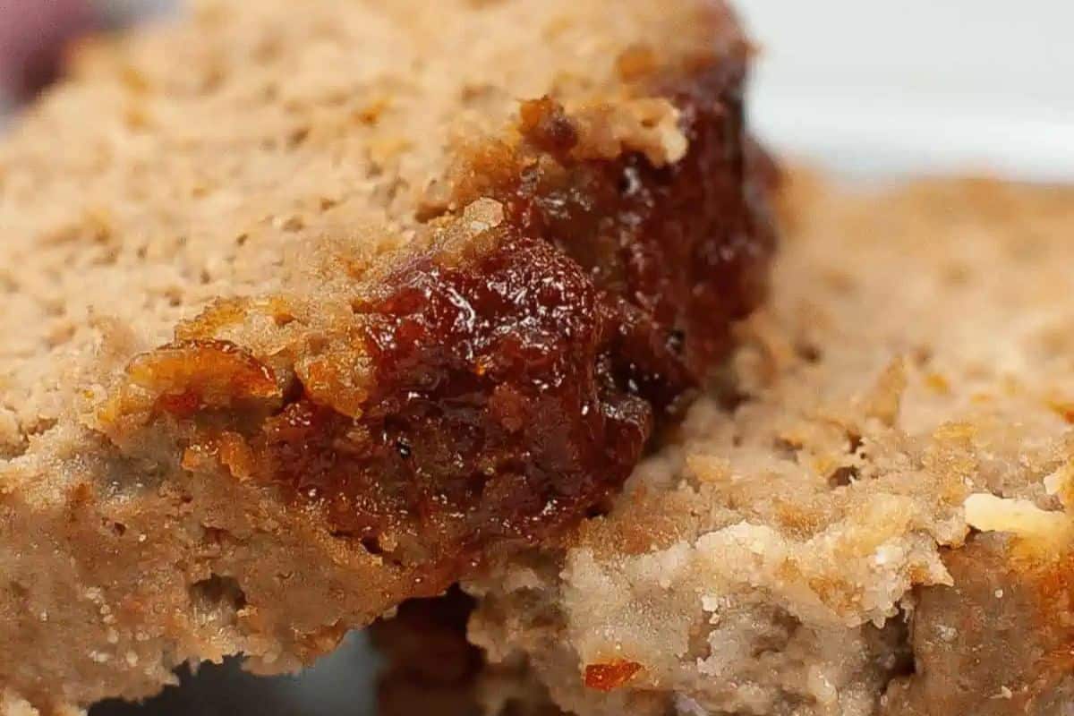 Close-up of two slices of meatloaf, with a glazed top and served on a white plate.