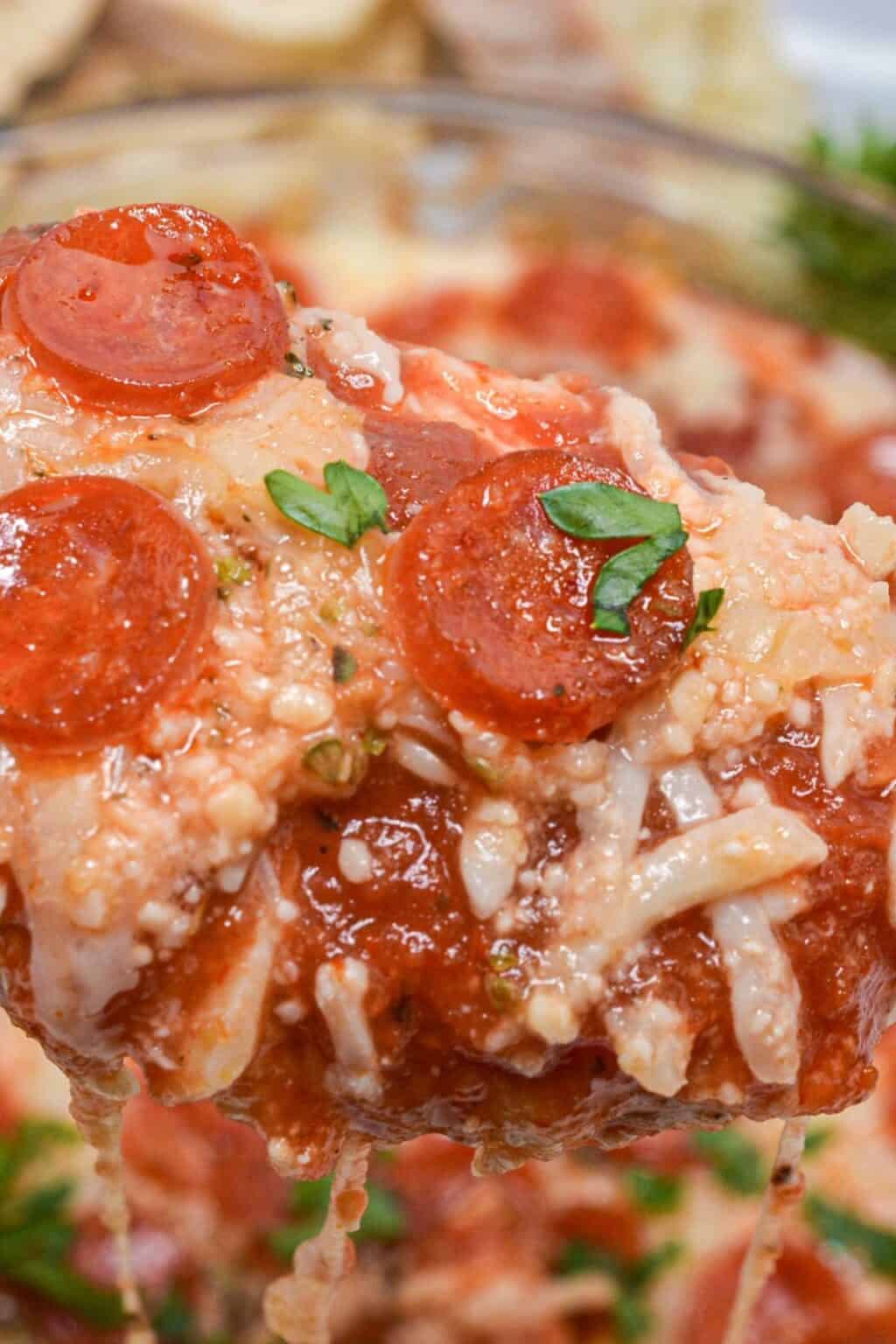 Close-up of a cheesy baked Pepperoni Dip, topped with tomato sauce, mini pepperoni slices, grated cheese, and fresh parsley.