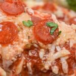Close-up of a cheesy baked Pepperoni Dip, topped with tomato sauce, mini pepperoni slices, grated cheese, and fresh parsley.