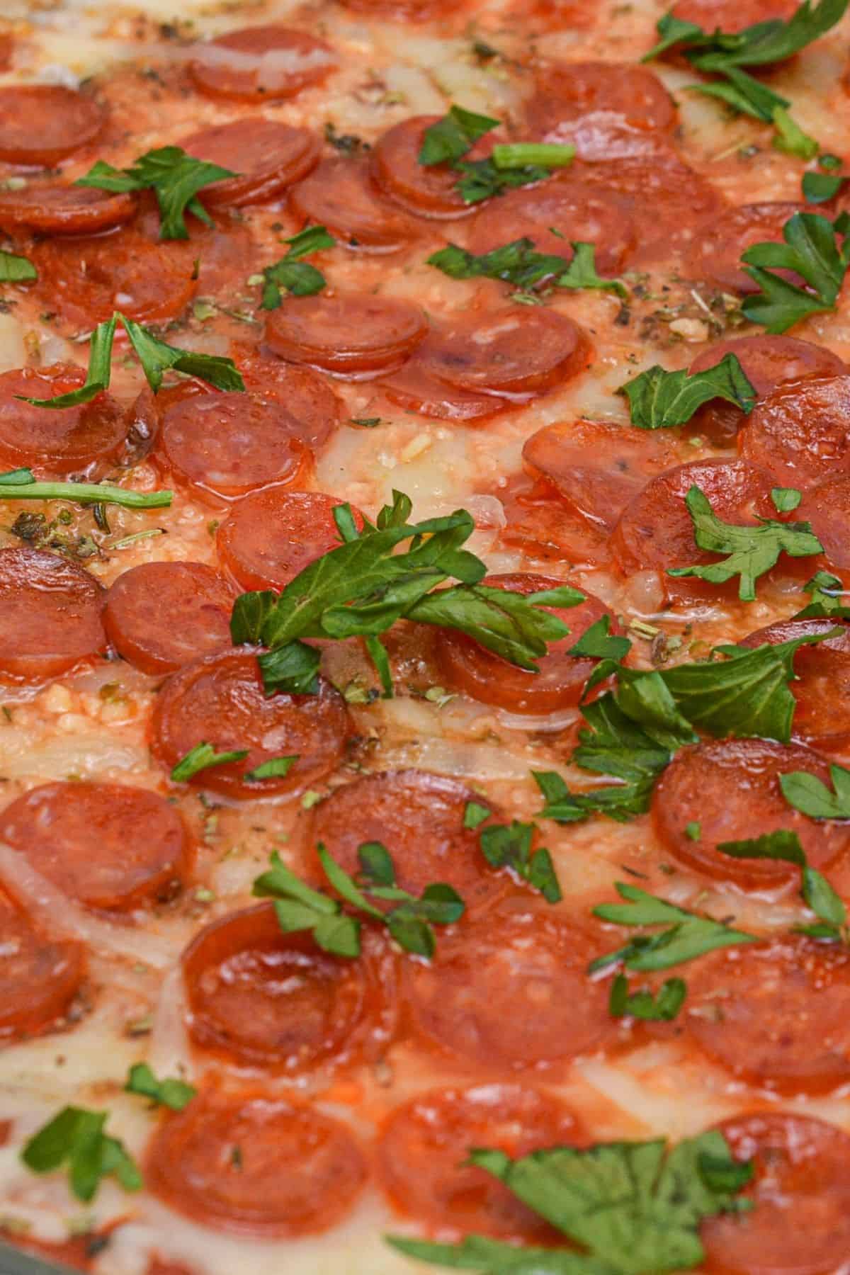 Close-up of a pepperoni pizza topped with melted cheese and garnished with fresh parsley leaves, reminiscent of the flavors found in a classic Pepperoni Dip.