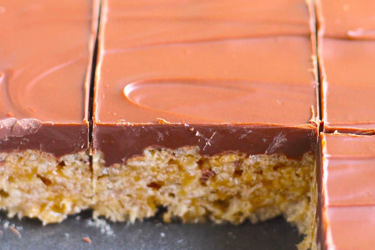 Close-up of chocolate-covered crispy rice treats, perfect as crowd-pleasing desserts for any creative bake sale, with one bar partially eaten to reveal the textured cereal layer beneath the smooth chocolate topping.