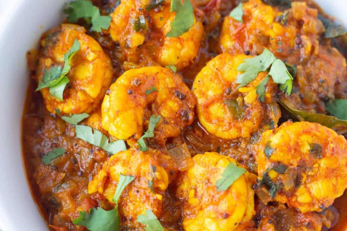 A bowl of restaurant-quality shrimp marsala garnished with fresh cilantro leaves, showcasing shrimp in a rich, spiced tomato-based sauce, perfect for home cooking.