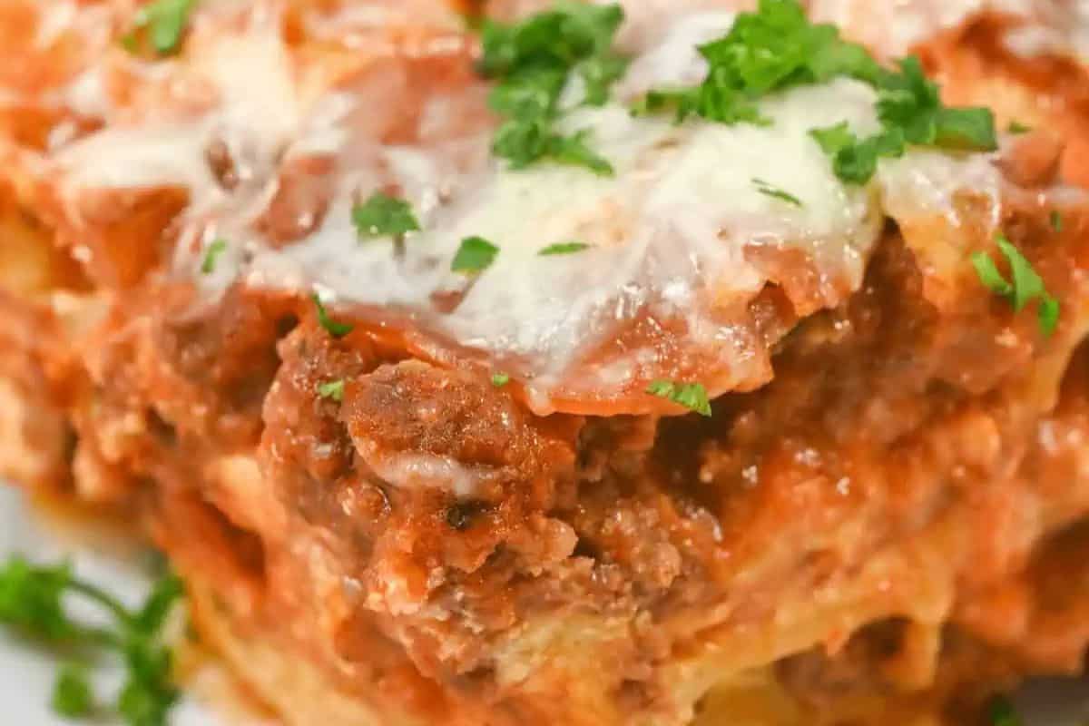 Close-up of a slice of layered lasagna, garnished with some parsley. 