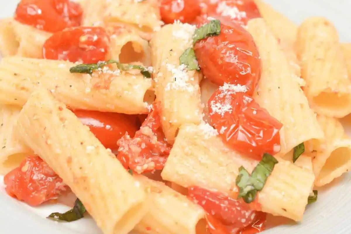 Rigatoni pasta with a creamy tomato sauce made from baked feta and cherry tomatoes, garnished with basil.