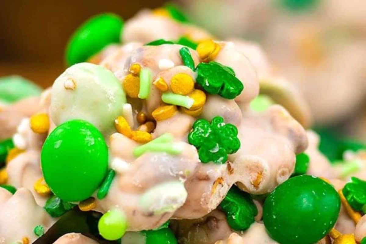 Close-up of cute treats coated in white chocolate, featuring green and brown candy pieces and sprinkles, perfect for celebrating St. Patrick’s Day with a sweet twist.