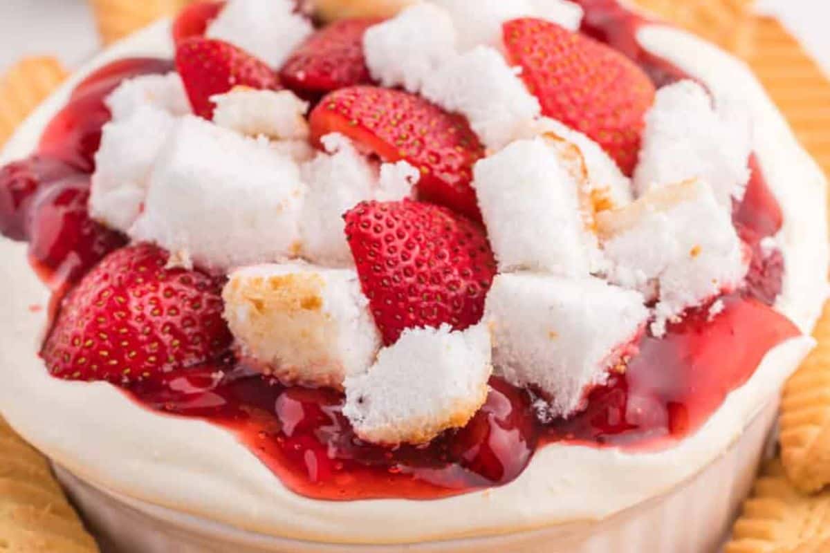 A delightful strawberry cheesecake dip perfect for Galentine's Day features sliced strawberries, sponge cake pieces, and whipped cream, all topped with strawberry sauce and surrounded by wafer cookies. Celebrate with your bestie using these festive recipes!.