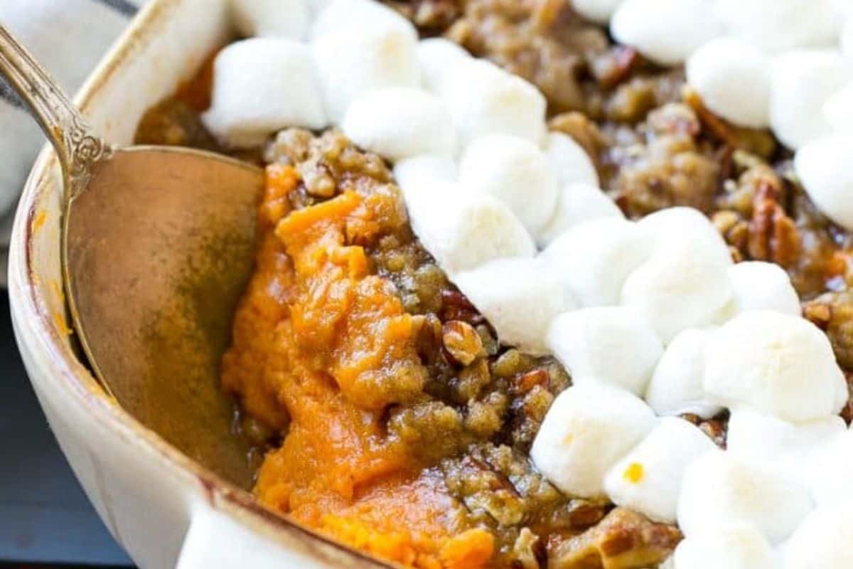 Close-up of a white dish of sweet potatoes topped with creamy marshmallows.