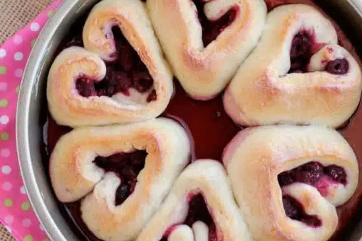 Heart-shaped pastries filled with berry compote arranged in a round baking pan, resting on a pink polka dot cloth—a charming Valentine's Day breakfast perfect for brunch recipes.