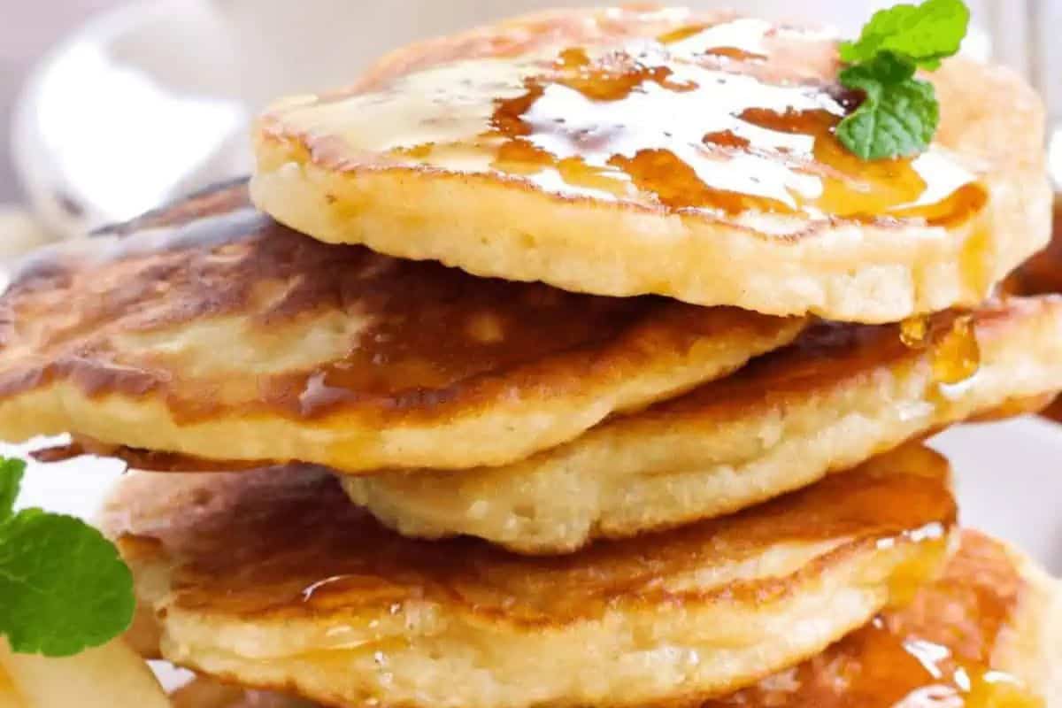 Stack of pancakes with syrup and butter, garnished with mint leaves. Perfect for your St. Patrick's Day brunch, these pancakes bring a festive twist to classic breakfast ideas.