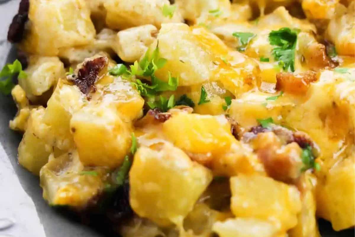 Close-up of a cheesy potato casserole topped with chopped parsley on a serving tray—a delicious addition to your brunch recipes, perfect for those who love sweet and savory flavors.