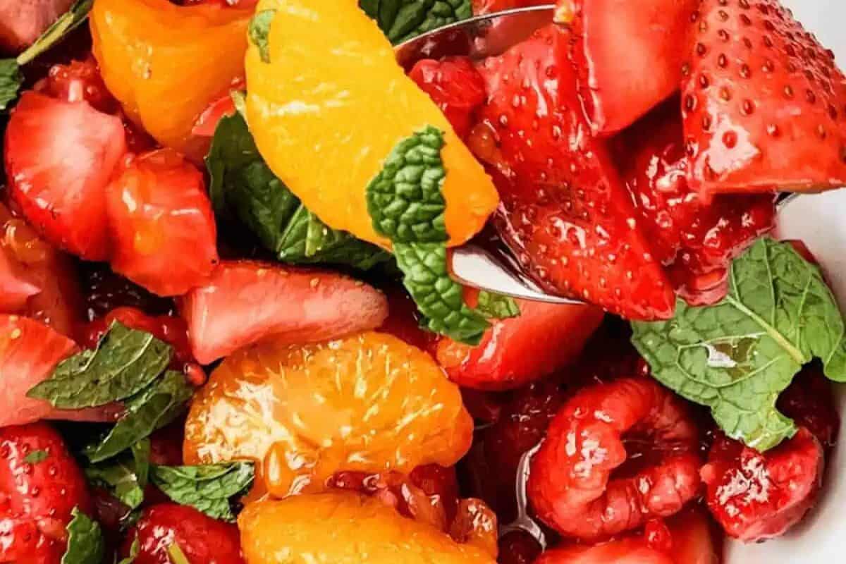 Close-up of a fruit salad with strawberries, raspberries, orange segments, and mint leaves—perfect for sweet and savory brunch recipes or a refreshing Valentine's Day breakfast.