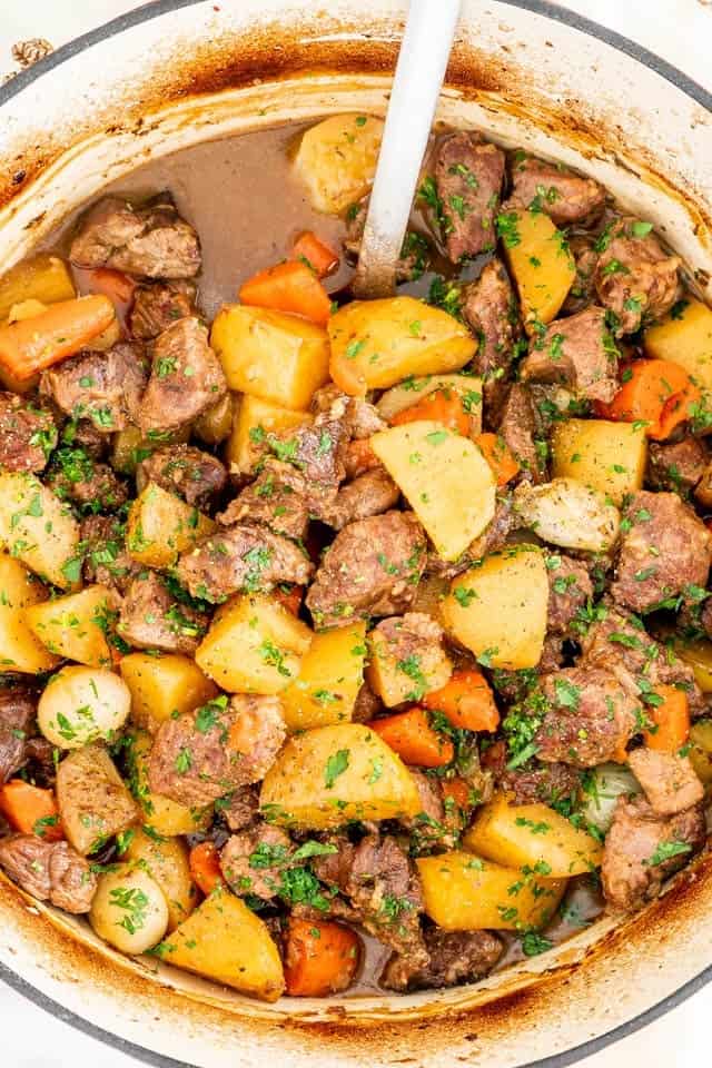 A pot of beef stew with chunks of beef, potatoes, carrots, and herbs in a rich broth evokes the spirit of Irish-inspired dinners. Perfectly paired with a serving spoon, it's an ideal choice for celebrating St. Patrick's Day.