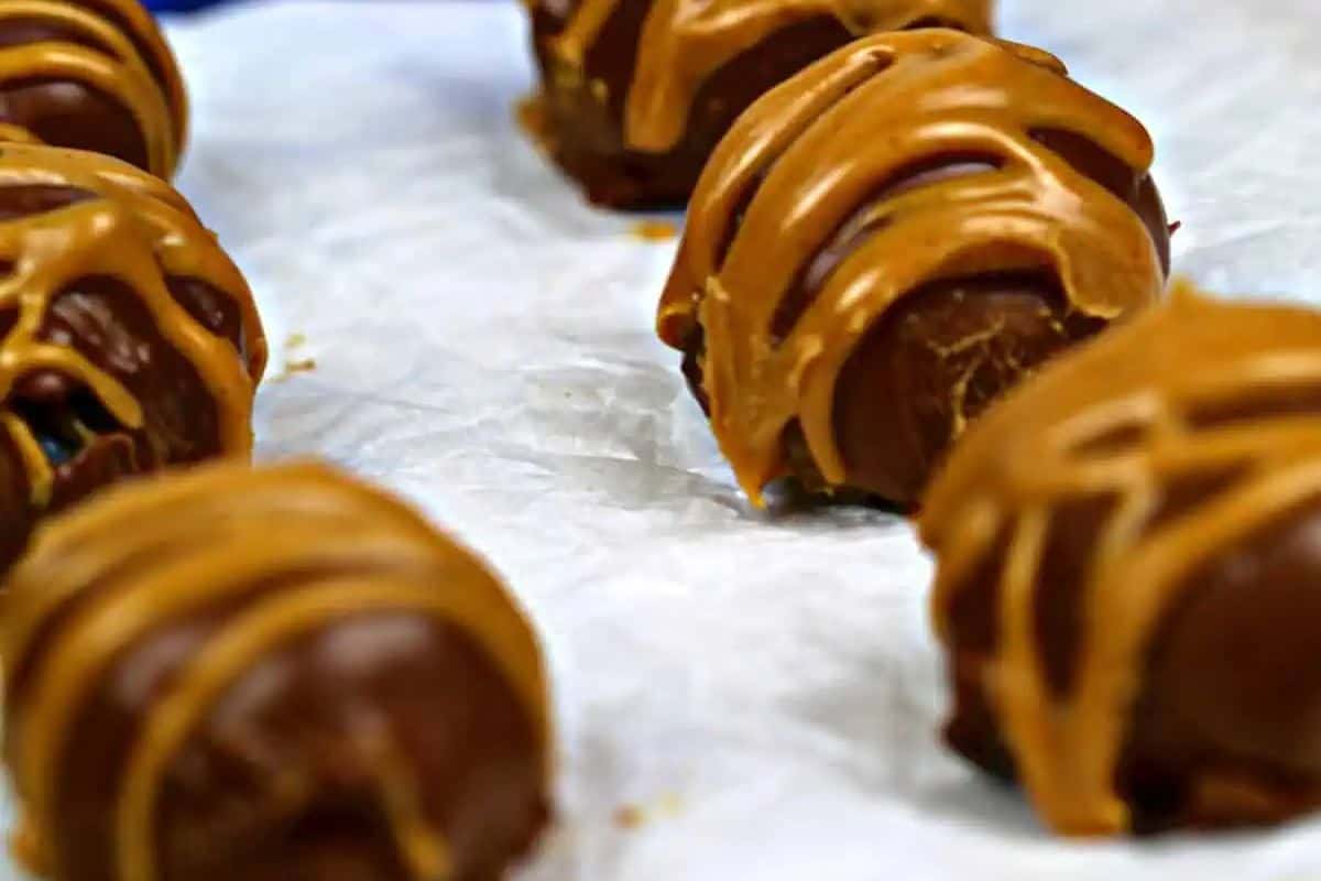 Close-up of round chocolate truffles drizzled with peanut butter, arranged on crumpled parchment paper—perfect crowd-pleasing desserts for any creative bake sale.