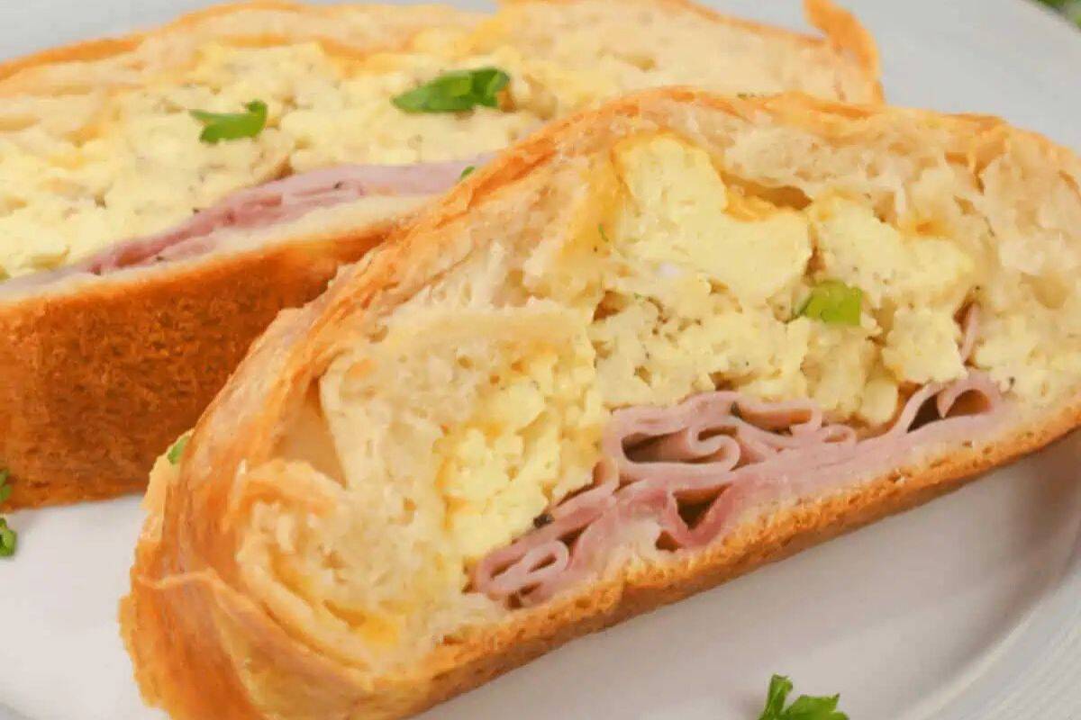 Two slices of stuffed bread filled with scrambled eggs, ham, and cheese, garnished with parsley on a white plate—perfect for sweet and savory brunch recipes or a special Valentine's Day breakfast.