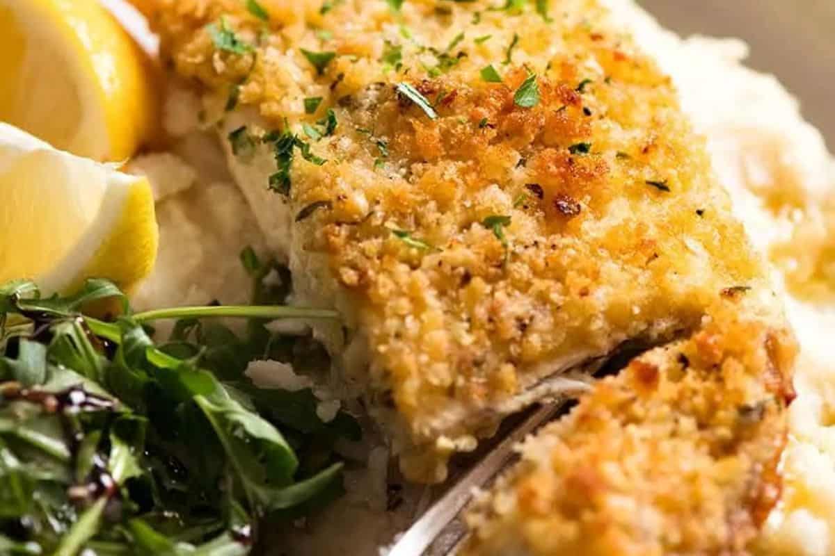 A breaded and baked fish fillet topped with herbs, served with rice, lemon wedges, and a side salad—one of those easy recipes perfect for Lent and a delicious addition to your favorite fish dishes.