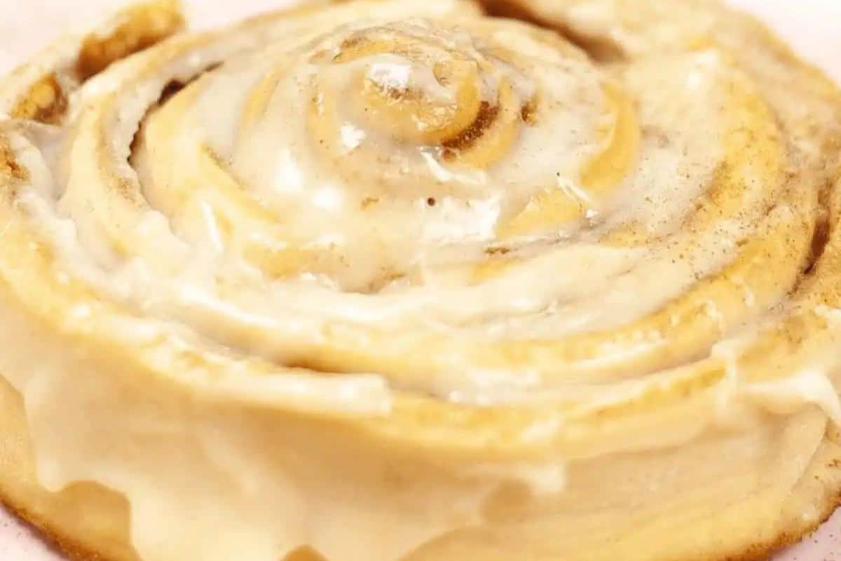 A glazed cinnamon roll, perfect for spring brunch recipes, boasts visible swirls and a light frosting on top. This treat is sure to impress anyone at the table.
