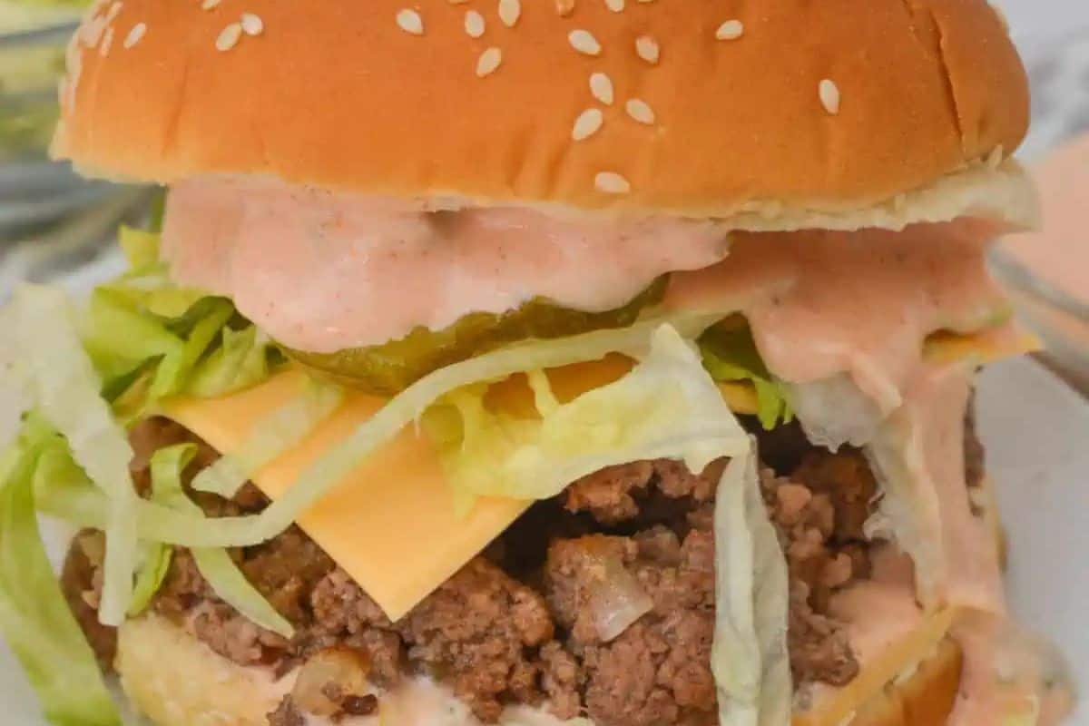 Big Mac Sloppy Joe with ground beef, cheese, lettuce, pickles, and pink sauce on a sesame seed bun.