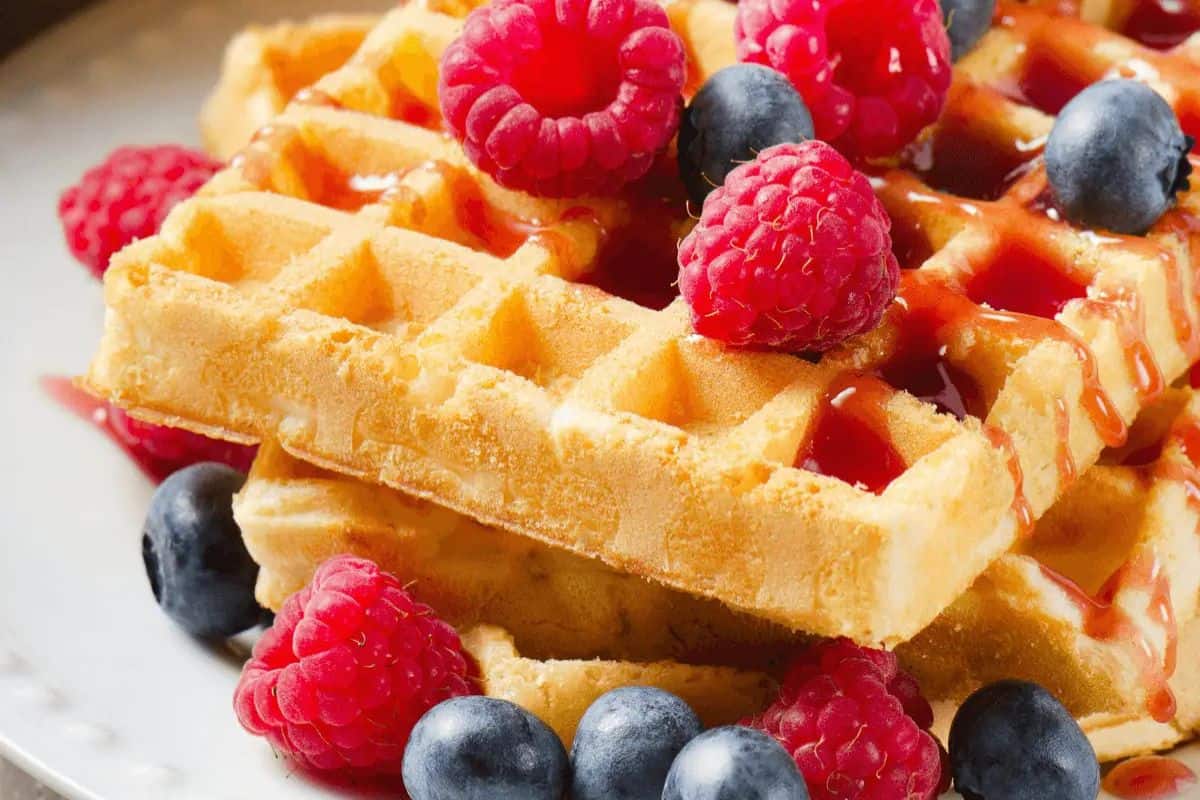 A delightful stack of waffles crowned with raspberries, blueberries, and a drizzle of syrup makes for the perfect highlight in spring brunch recipes.