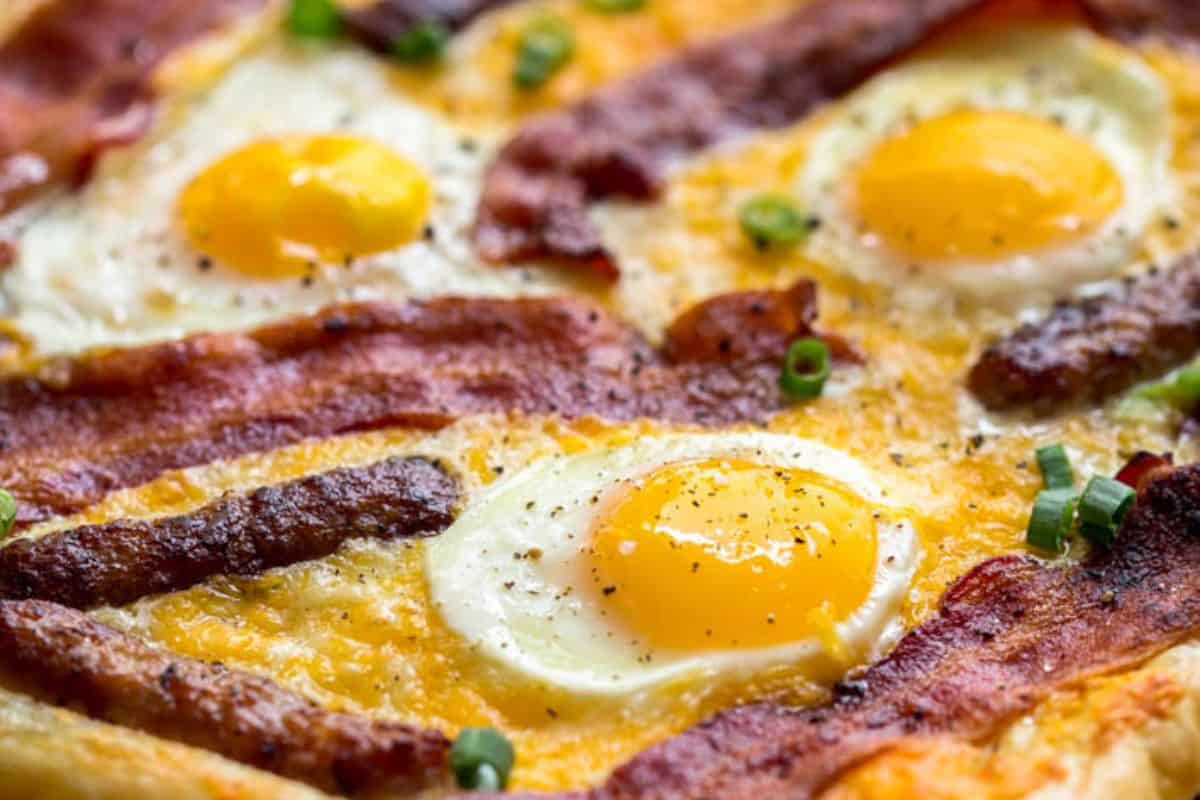 Indulge in an Easter brunch delight with a pizza topped with sunny-side-up eggs, crispy bacon strips, melted cheese, and fresh chopped green onions.