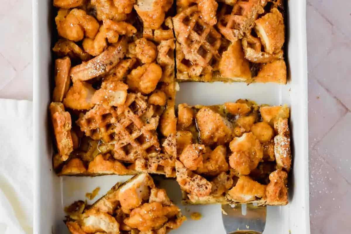 Easter Brunch delight: A baked dish of chicken and waffles cut into pieces in a rectangular pan, perfect for celebrating with family. A spatula rests at the corner, ready to serve up this festive treat.