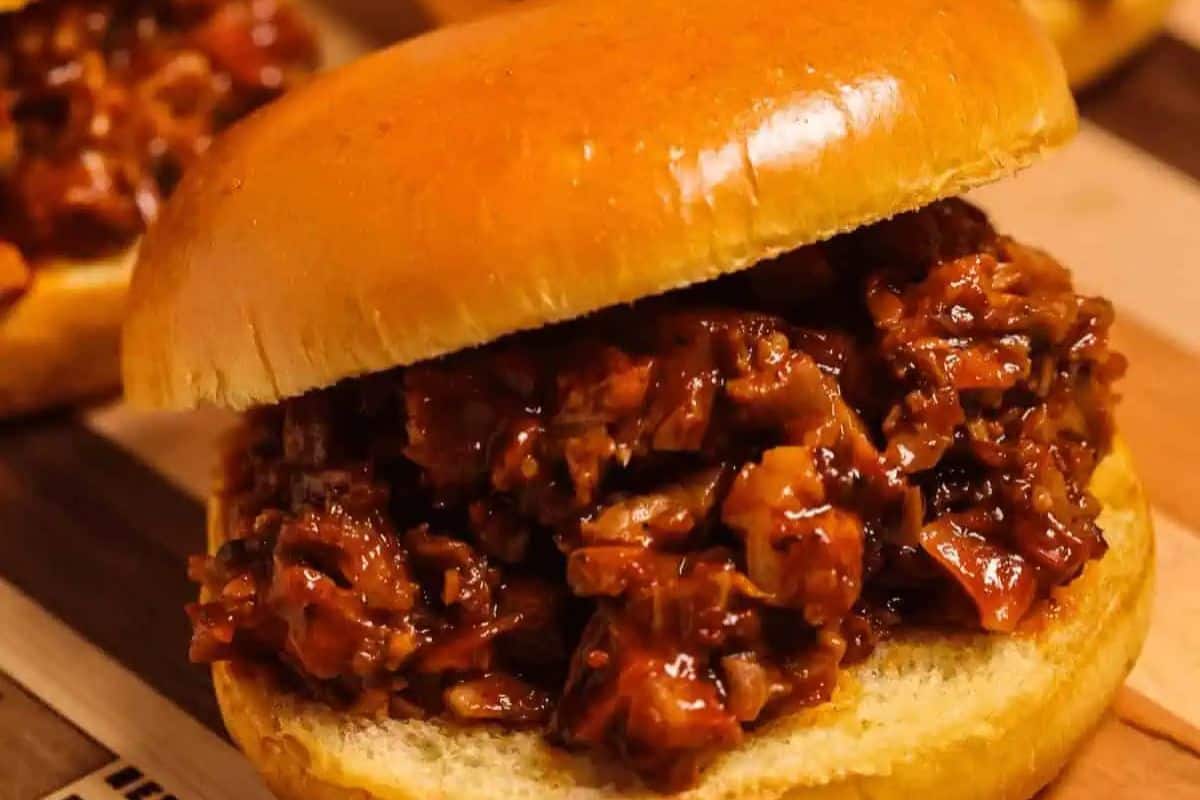 Sandwich featuring chopped brisket on a wodden board.