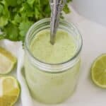 A jar of the drizzle with a spoon in it.