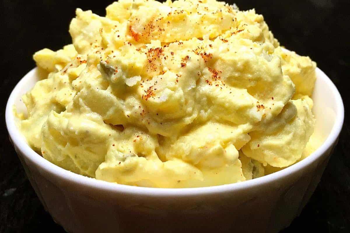 A bowl of creamy potato salad, perfect for Easter side dishes, topped with a sprinkle of paprika.