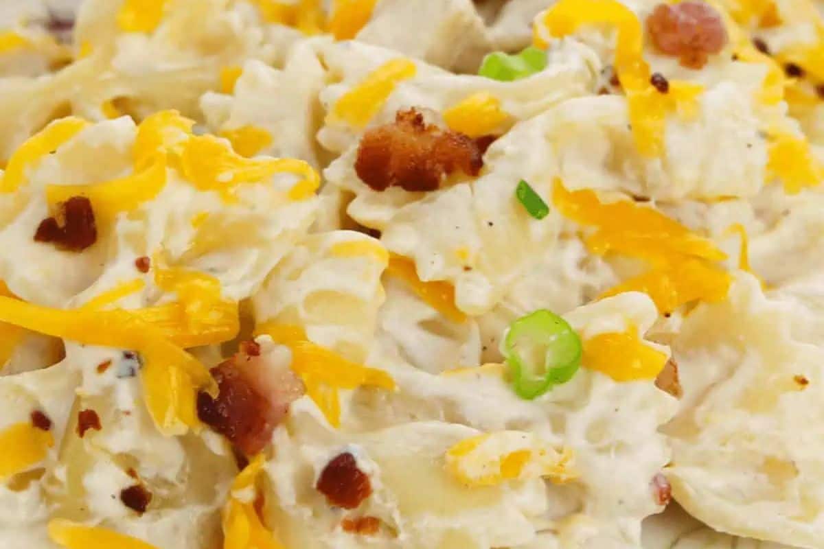 Close-up of creamy crack chicken pasta, perfect for beginners looking to master pasta dishes, topped with shredded cheese, bacon bits, and chopped green onions.
