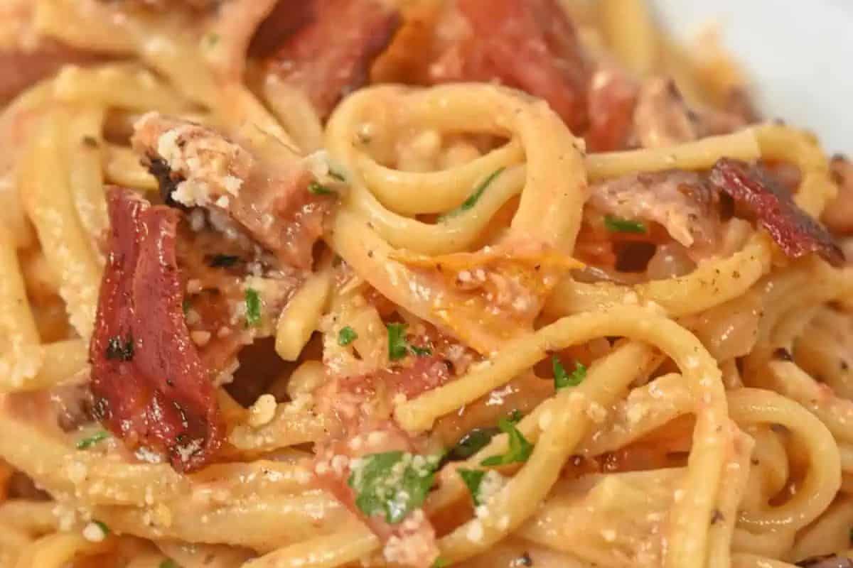 Close-up of a beginner-friendly pasta dish featuring spaghetti with bacon, tomato, herbs, and a creamy sauce—a perfect way to master the art of simple yet delicious cooking.