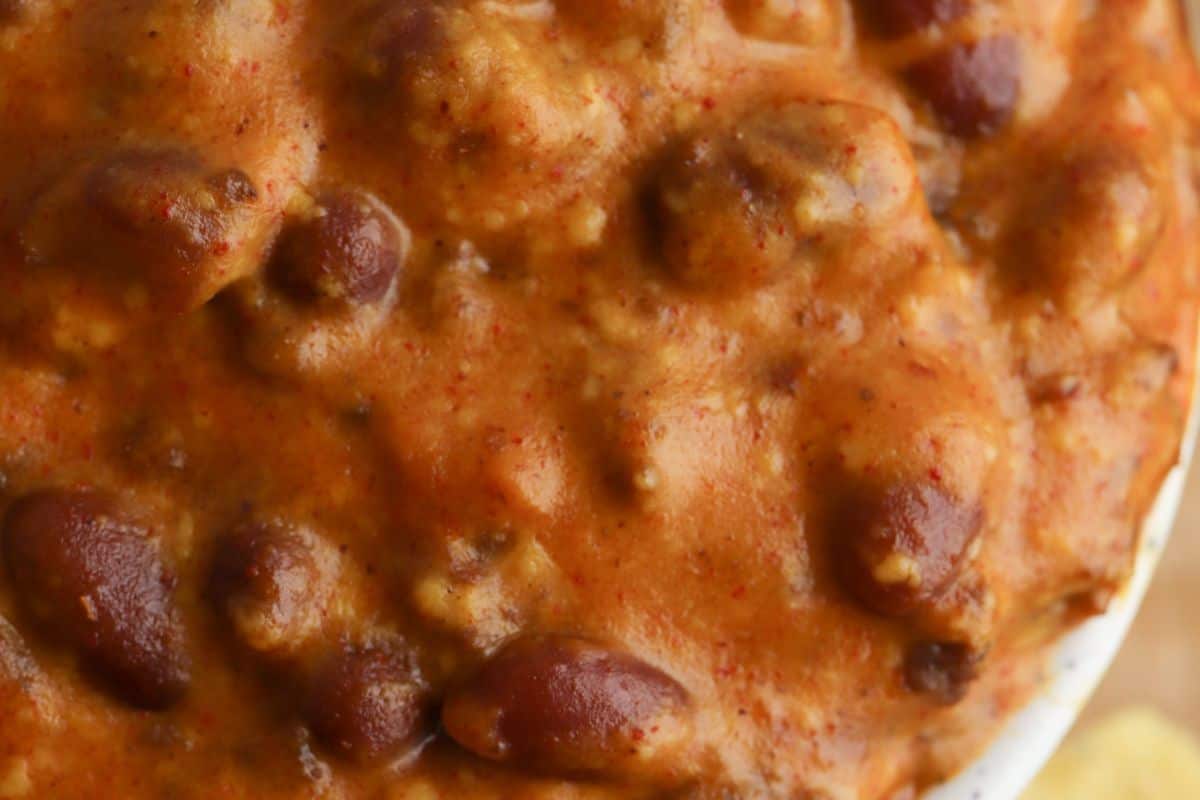 Close-up of a creamy chili with red beans and meat, showcasing the thick, textured consistency of this perfect party dip. Ideal for Cinco de Mayo celebrations, it's a crowd-pleaser that pairs well with tortilla chips.